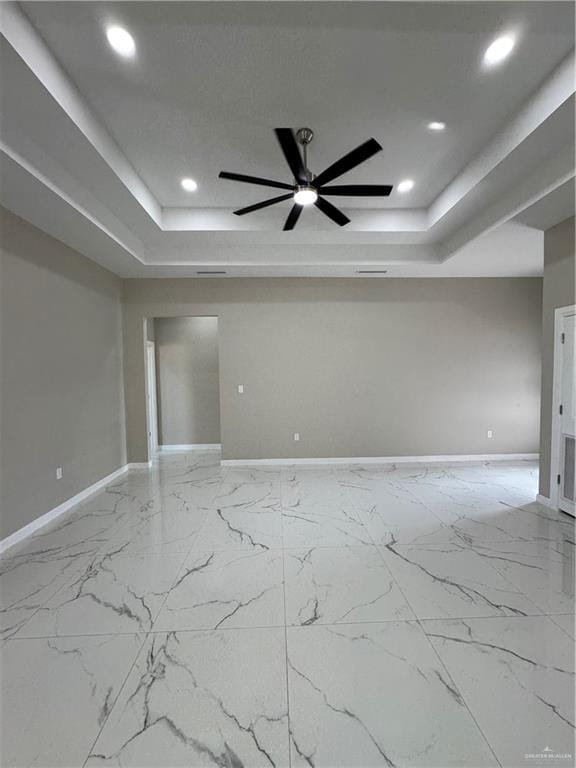 spare room featuring a raised ceiling and ceiling fan