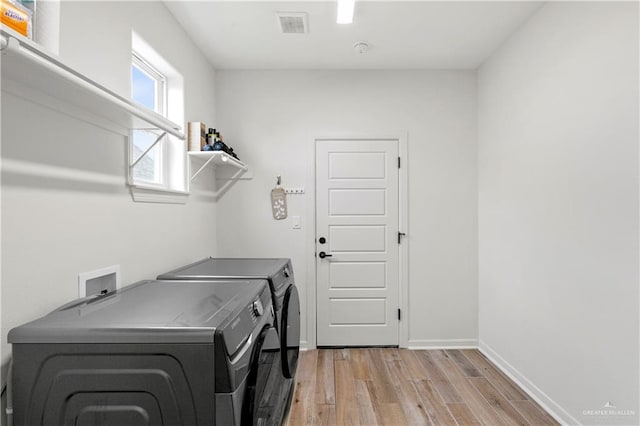 clothes washing area with washer and clothes dryer and light hardwood / wood-style floors