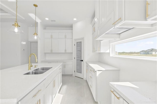 kitchen with white cabinets, decorative light fixtures, light stone countertops, and sink