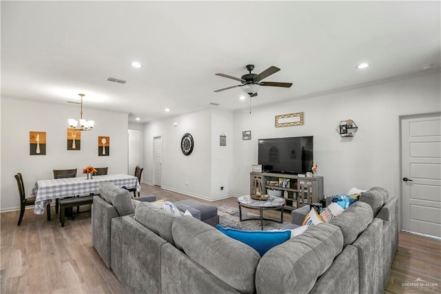 living room featuring ceiling fan with notable chandelier, light hardwood / wood-style floors, and crown molding