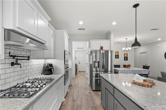 kitchen with appliances with stainless steel finishes, light stone counters, light hardwood / wood-style flooring, white cabinetry, and range hood