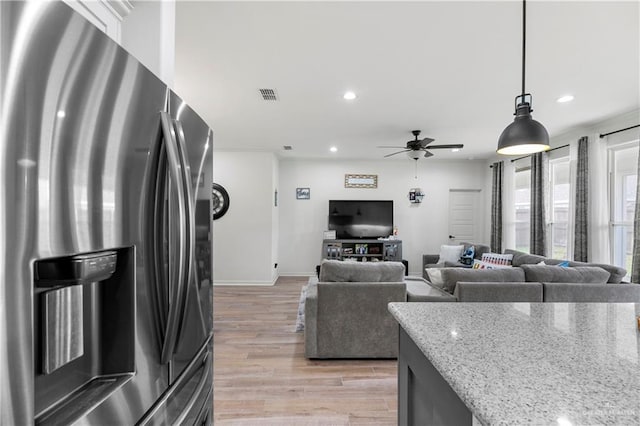 kitchen featuring ceiling fan, light stone counters, light hardwood / wood-style flooring, stainless steel refrigerator with ice dispenser, and decorative light fixtures