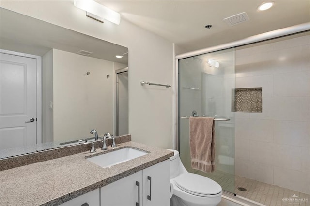 bathroom with vanity, toilet, and a shower with door