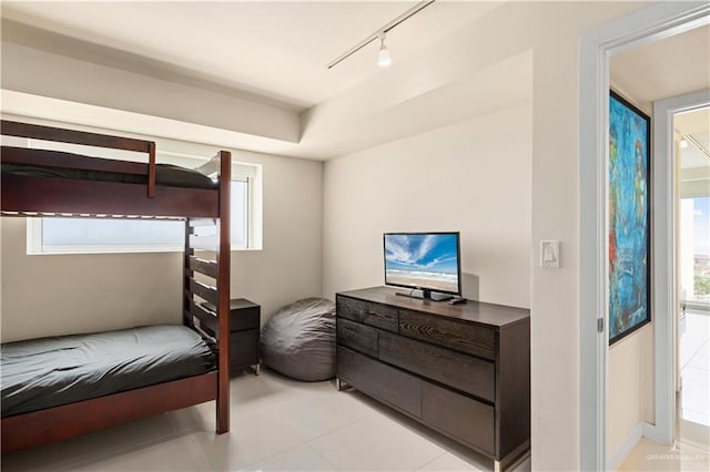 tiled bedroom featuring track lighting and multiple windows