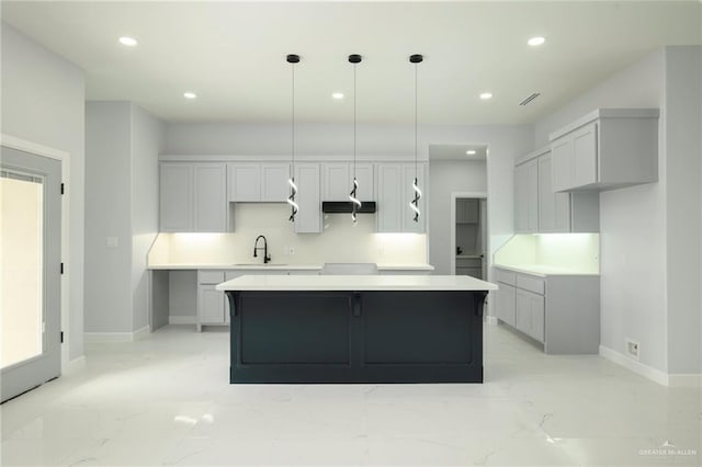 kitchen with gray cabinets, decorative light fixtures, a center island, and sink