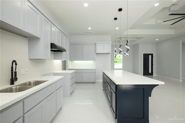 kitchen with white cabinets, a center island, sink, and hanging light fixtures