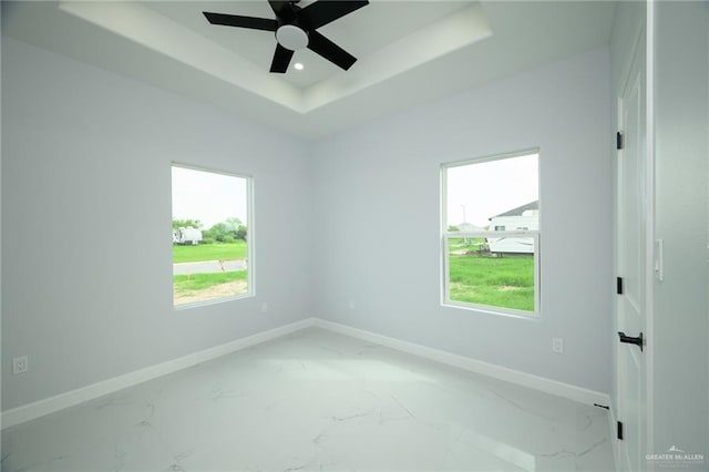 spare room featuring a tray ceiling and ceiling fan