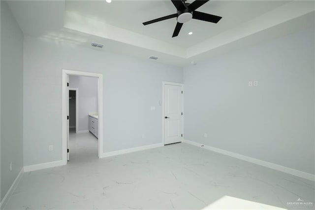 unfurnished bedroom featuring ceiling fan, a raised ceiling, and ensuite bathroom