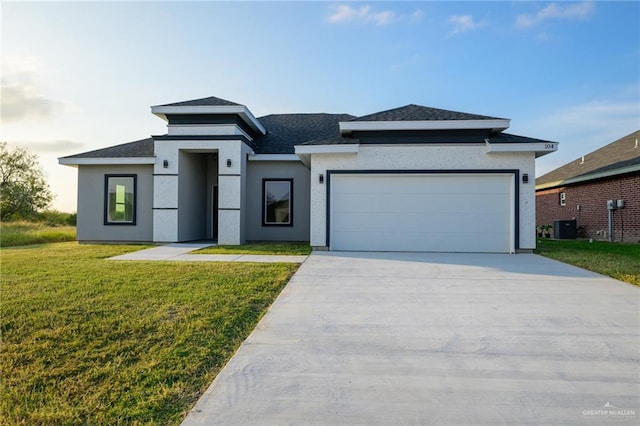 prairie-style house with a garage, a front lawn, and central air condition unit