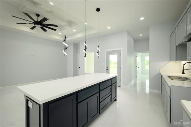 kitchen featuring ceiling fan, sink, a center island, decorative light fixtures, and gray cabinets