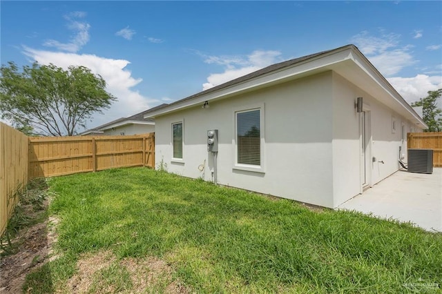 rear view of property featuring a lawn, cooling unit, and a patio