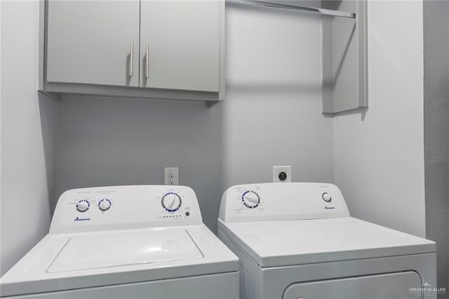 clothes washing area featuring washer and dryer and cabinets