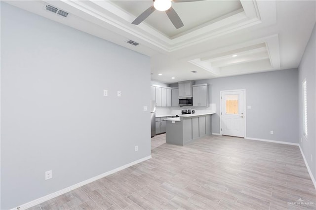 unfurnished living room with ceiling fan, light hardwood / wood-style floors, and a tray ceiling