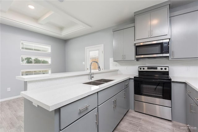 kitchen featuring gray cabinets, kitchen peninsula, sink, and appliances with stainless steel finishes