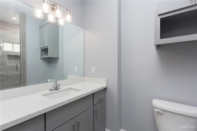 bathroom featuring vanity, toilet, and a shower with shower door