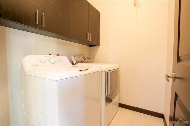 laundry area with cabinets, washing machine and dryer, and light tile patterned flooring