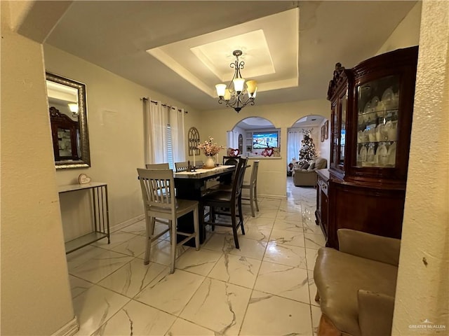 dining space with a raised ceiling and an inviting chandelier