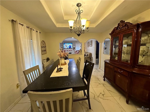 dining space featuring a raised ceiling and a chandelier