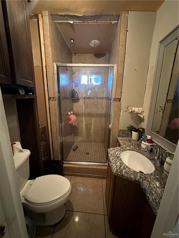 bathroom with toilet, vanity, tile patterned floors, and walk in shower