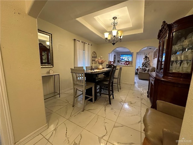 dining space featuring a tray ceiling and a notable chandelier