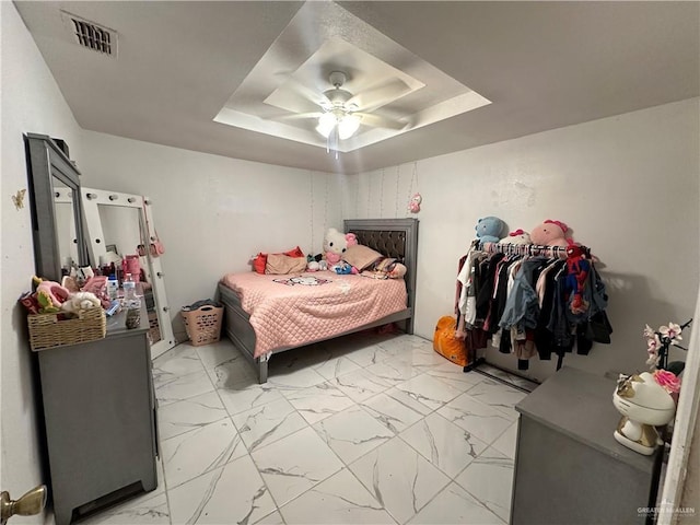 bedroom with ceiling fan and a tray ceiling