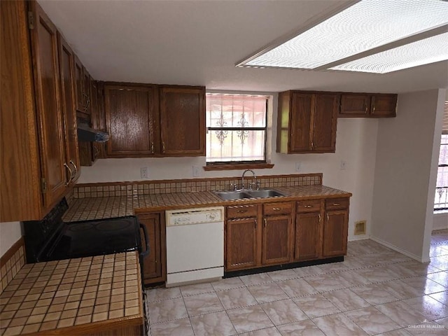 kitchen with white dishwasher, tile counters, sink, and exhaust hood