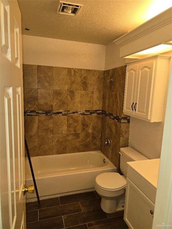 full bathroom with toilet, a textured ceiling, vanity, and tiled shower / bath combo