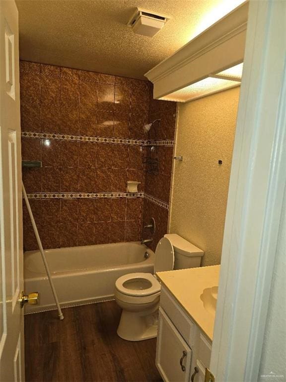 full bathroom featuring hardwood / wood-style floors, a textured ceiling, toilet, vanity, and tiled shower / bath