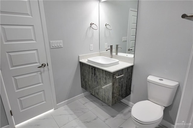 bathroom with toilet, marble finish floor, baseboards, and vanity