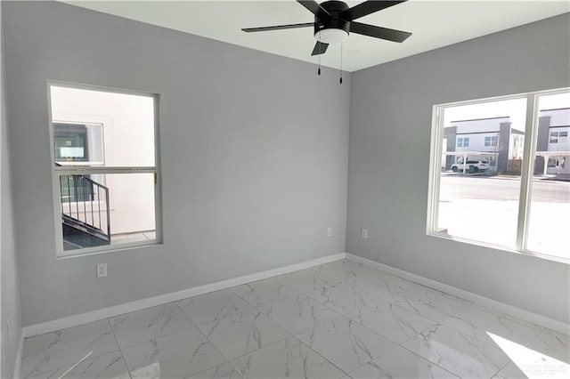 spare room with marble finish floor, plenty of natural light, and baseboards