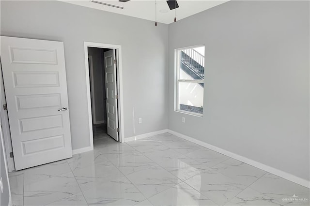 unfurnished bedroom with marble finish floor and baseboards