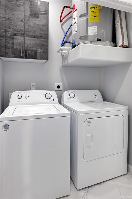 clothes washing area with cabinet space, marble finish floor, water heater, and washer and dryer