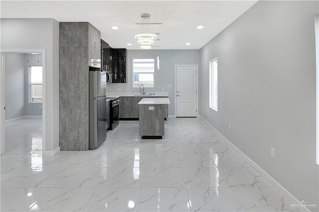 kitchen featuring marble finish floor, pendant lighting, stainless steel appliances, light countertops, and a kitchen island