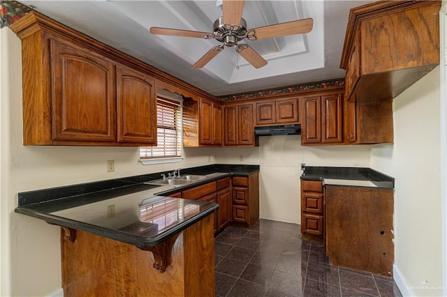 kitchen with a peninsula, ceiling fan, range hood, a sink, and granite finish floor