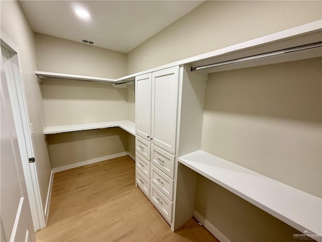 spacious closet with built in desk and light hardwood / wood-style floors