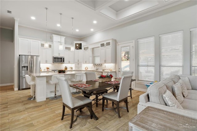 dining space featuring sink, crown molding, and light hardwood / wood-style flooring