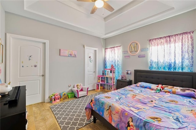 bedroom featuring hardwood / wood-style floors, a raised ceiling, and ceiling fan