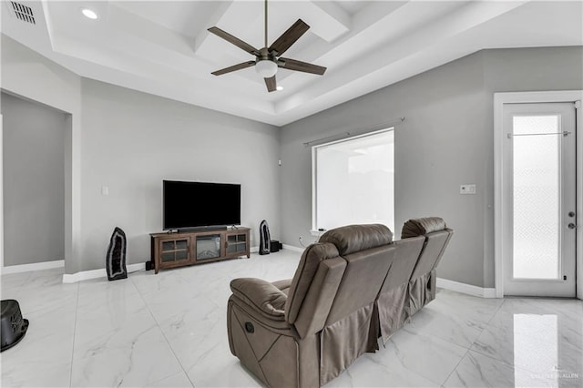 living room featuring a raised ceiling and ceiling fan