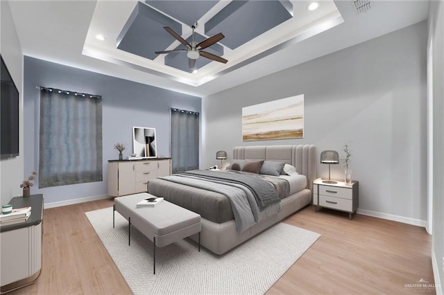 bedroom featuring ceiling fan, light hardwood / wood-style floors, and a raised ceiling