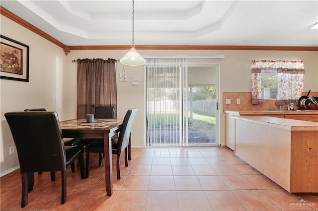 dining area featuring a raised ceiling, crown molding, sink, and light tile patterned flooring