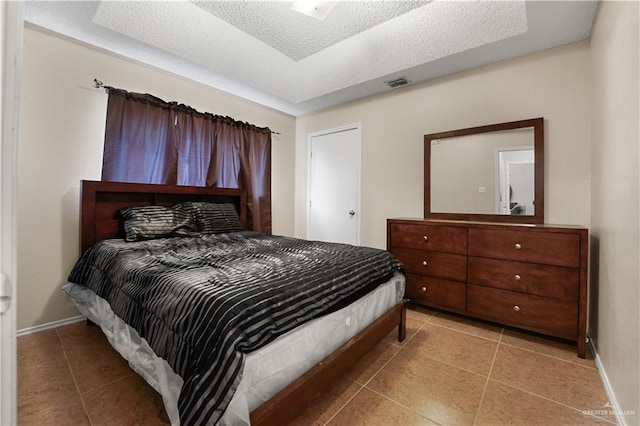 bedroom featuring light tile patterned floors and a textured ceiling