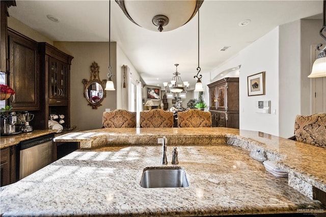 1901 Pecos St, Mission, TX 78572 - kitchen with dishwasher, light stone countertops, dark brown cabinetry, a chandelier, and decorative light fixtures