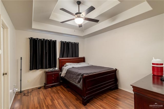 bedroom featuring dark hardwood / wood-style floors, a raised ceiling, and ceiling fan