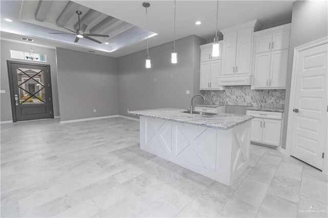 kitchen with a center island with sink, white cabinets, and sink