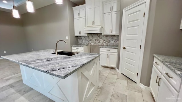 kitchen with a center island with sink, white cabinetry, and sink