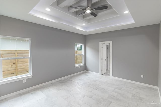 unfurnished room with ceiling fan, a tray ceiling, and baseboards