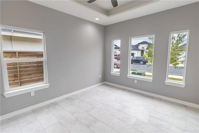 spare room featuring a tray ceiling, recessed lighting, a ceiling fan, and baseboards