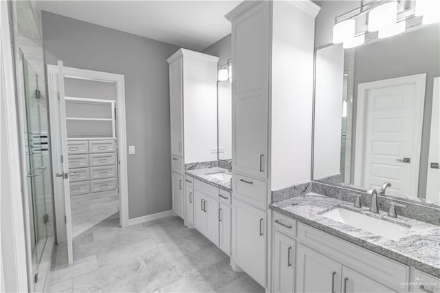 full bathroom featuring a stall shower, a sink, marble finish floor, a walk in closet, and two vanities