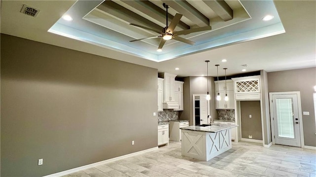 kitchen with a center island with sink and a tray ceiling