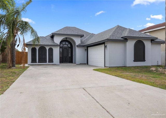 604 Hackberry Ave, Mission, TX 78572 - french country style house with a garage, concrete driveway, a shingled roof, and stucco siding
